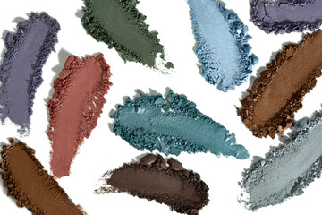 Smears of various colorful powdered eyeshadows or pigments arranged artistically on a white...