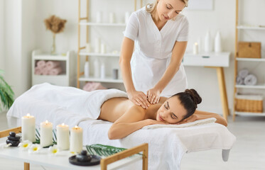 Woman enjoying aroma massage in spa centre, sleeping while lying on massage table, undergoing body...
