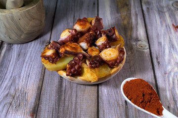 Galician-style octopus pieces served with a spoonful of paprika, isolated on a white background....