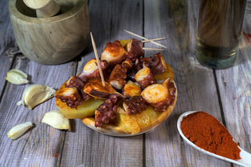 Galician-style octopus pieces served with a spoonful of paprika, isolated on a white background. Traditional Spanish seafood seasoning concept