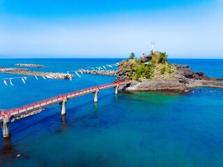糸魚川市能生の弁天岩と青い海、空に舞う鯉のぼり｜5月の空撮風景