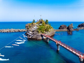 糸魚川市能生の弁天岩と青い海、空に舞う鯉のぼり｜5月の空撮風景