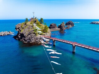 糸魚川市能生の弁天岩と青い海、空に舞う鯉のぼり｜5月の空撮風景