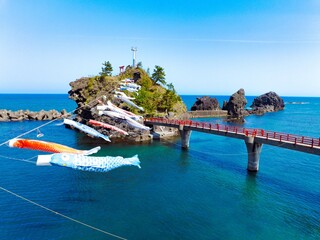 糸魚川市能生の弁天岩と青い海、空に舞う鯉のぼり｜5月の空撮風景