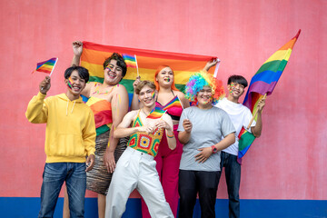 Happy group of young Asian friends having fun while holding rainbow flags celebrating Gay Pride...