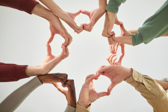 Unknown diverse people shaping heart sign with hands, posing in circle, demonstrating community, support and love, isolated over white background. People equality and justice in society - Powered by Adobe