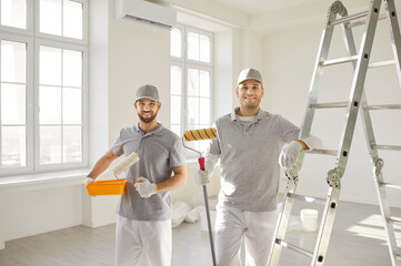 Happy professional painting service, painter team, construction workers wearing uniform doing...