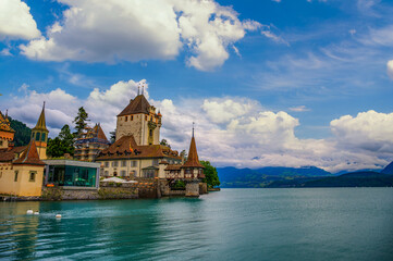 Obraz premium Historic Oberhofen Castle on the shore of Lake Thun with Swiss Alps in the distance, Switzerland