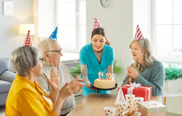 Birthday in nursery house. Nurse and three senior people celebrating anniversary of friend, giving...