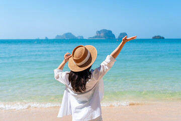 Young Asian woman relaxing and enjoying at beautiful white sand beach on sunny day, Travel on summer vacation