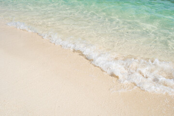 Beautiful tropical white sand beach with wave foam and transparent sea, Summer vacation and Travel background with copy space