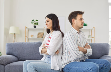 Sad and offended family couple sits on a couch at home, appearing angry during a domestic quarrel....