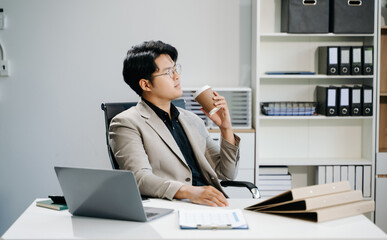 Young business man working at office with laptop, tablet and taking notes on the paper..