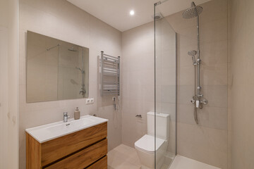 Modern bathroom with chrome towel warmer, wood vanity and large wall mirror above sink