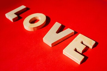 Wooden letters forming the word love on a vibrant red background. Perfect for themes of love, romantic decorations, Valentine's Day, and heartfelt messages in greeting cards or campaigns.