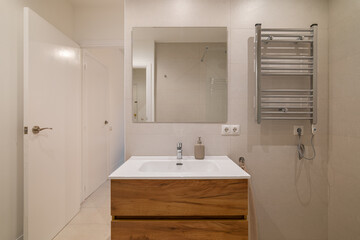 Modern bathroom with wood vanity, large wall mirror, chrome towel warmer and glass shower area