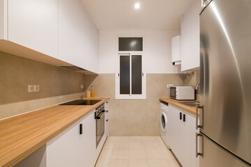 Bright kitchen with wood countertops, white cabinets and modern appliances in compact space