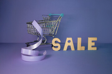 Mini shopping cart with blue ribbon and wooden letters spelling 