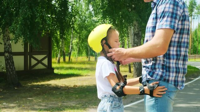 Father helped her daughter wear a yellow helmet while enjoying time together in the park