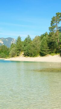 Turquoise lake Urisee surrounded by pine forests and rugged hills in Reutte Tirol, calm highland setting for natural peace