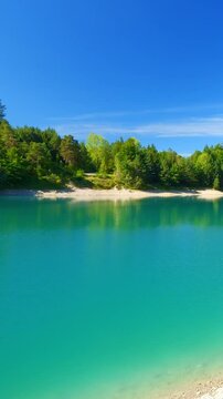 Quiet mountain lake Urisee with glistening blue water, pine-covered hills, and summer light in the Austrian Tyrol
