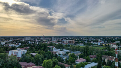 Aerial view of Pancevo, Serbia, at sunset in spring. The city is bathed in warm light, with green trees, houses, and buildings forming a beautiful and peaceful landscape.