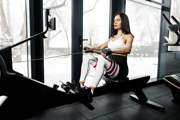 Fototapeta premium Flexible young woman stretching her legs in the gym. Female posing on the floor