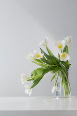 white tulips in glass vase in white interior