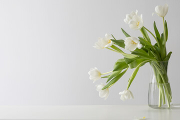 white tulips in glass vase in white interior