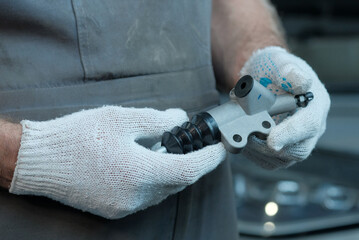 Car service. Car repair and maintenance.The clutch cylinder is in the hands of an auto mechanic. Serviceability control, inspection of new spare parts before replacement.