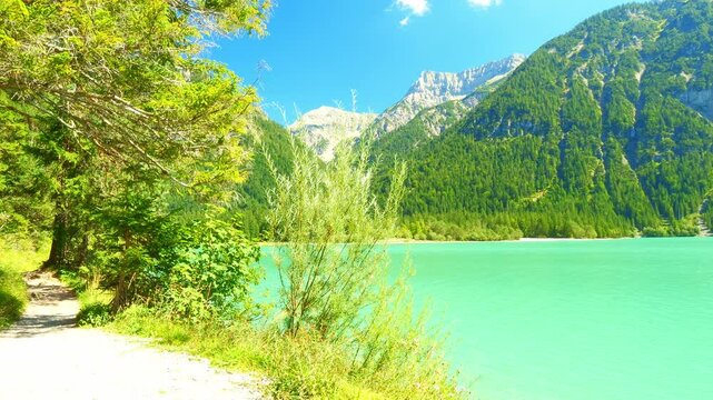 Tranquil turquoise lake in the Austrian Alps near Heiterwang with forested slopes and calm summer skies in a serene mountain setting