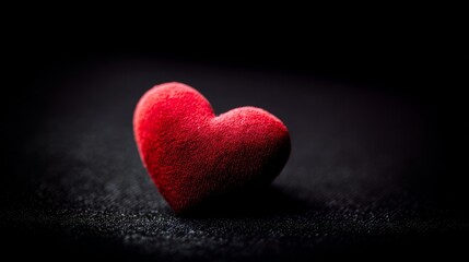 Obraz premium Red heart shape on black background, soft ambient lighting, f/2.8, minimalistic and emotional composition.