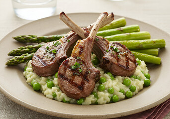 Gourmet grilled lamb chops with lush green asparagus and peas, creating a warm dining Presentation war grilled lamb chops paired with vibrant green peas and asparagus, ideal for an elegant meal inspir