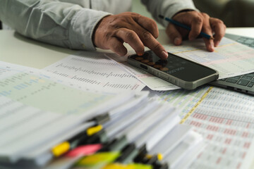 businessman uses a calculator and paperwork to analyze finances, investments, and tax reports at his desk calculator and digital tablet. business financial reports and data analysis