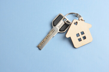 Keys with Keychain in the shape of a house on a blue background.