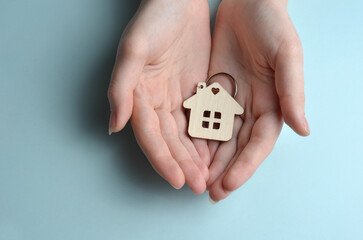 House keychain in hands. Blue background.