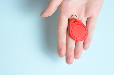 Red plastic intercom keychain. Blue background.