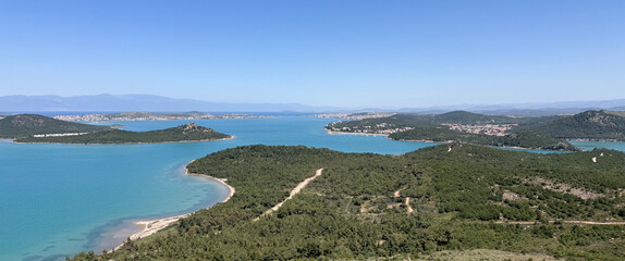 Aerial panoramic view of turquoise waters, lush green islands, and a clear blue sky. Ideal for nature, travel, and Mediterranean-themed visuals.
