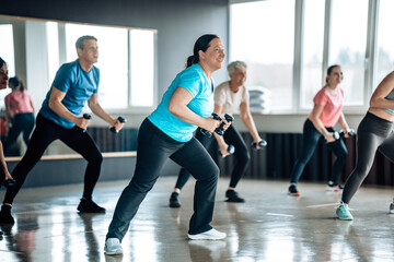 Diverse people lifting dumbbells together in a gym. Active lifestyle, physical fitness, and training routine