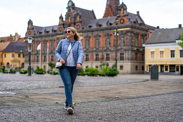 Obraz premium Beautiful mature woman walking through old town of Malmo in Sweden on autumn day. Front view