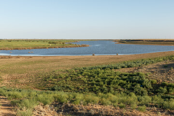River landscape in Kazakhstan showing calm waters and lush greenery during the evening light