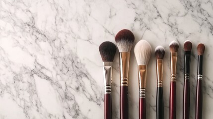 Flat lay of assorted makeup brushes on a marble background with soft lighting