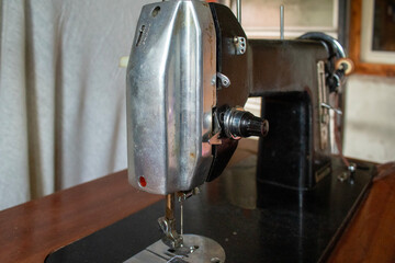 Rear angled view of a vintage sewing machine showing its body, metal wheel, and mechanical structure. Ideal for visuals emphasizing engineering, craftsmanship, and retro design.