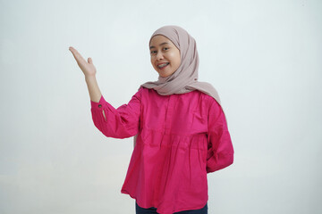 Smiling Young Asian Woman in Hijab Gesturing Upward with Open Hand isolated on White Background