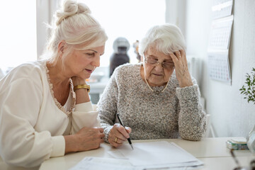 Woman helping her elderly mother preparing financial documents
