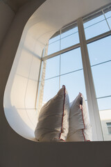 Two fluffy pillows are comfortably resting on a spacious window sill, directly in front of a large, inviting window that lets in sunshine