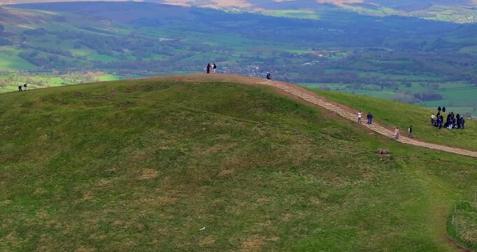 Aerial video of hikers at the top of Mam Tor with Castleton on the background. Peak District - UK 