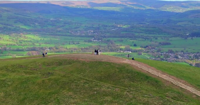 Aerial video of hikers at the top of Mam Tor with Castleton on the background. Peak District - UK 