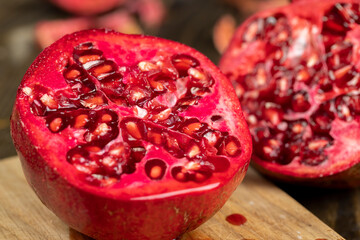 sliced ripe pomegranate on a black table, sweet red pomegranate cut into pieces during cooking,...