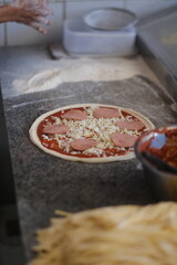 Pepperoni pizza in preparation on a floured countertop